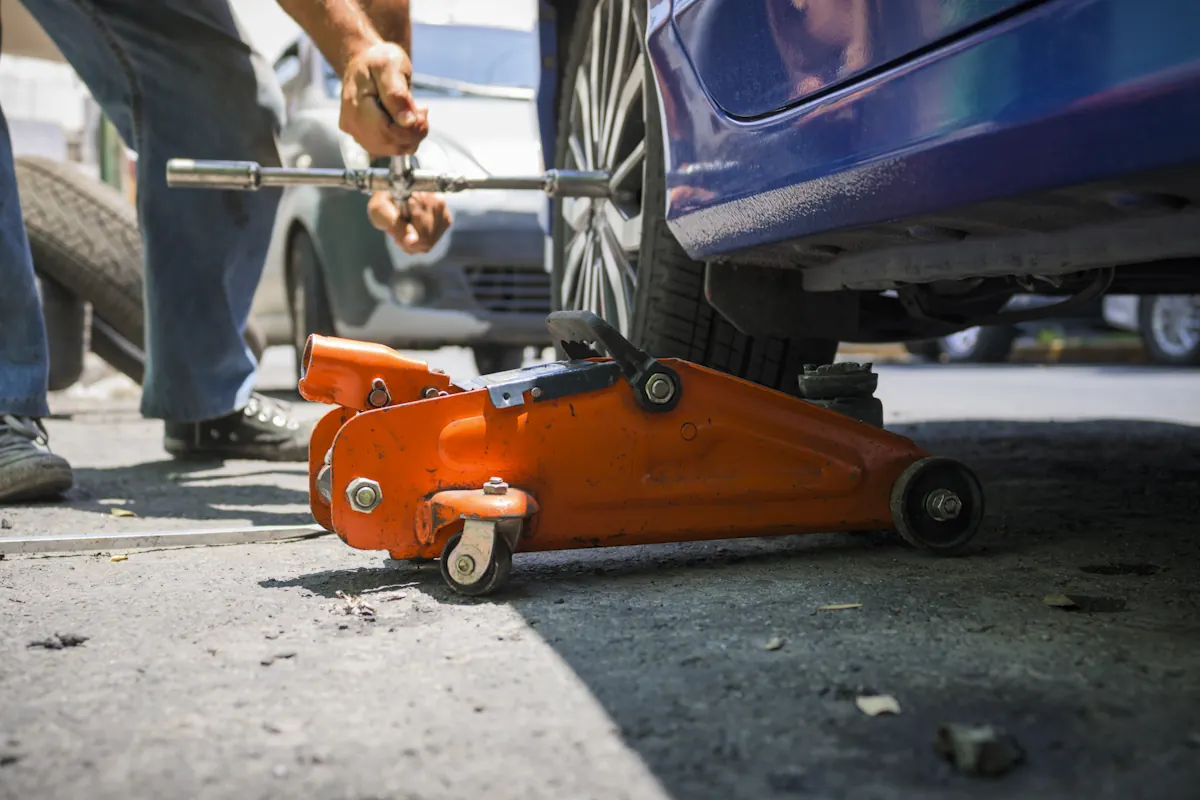 Un homme qui change un pneu avec un cric hydraulique