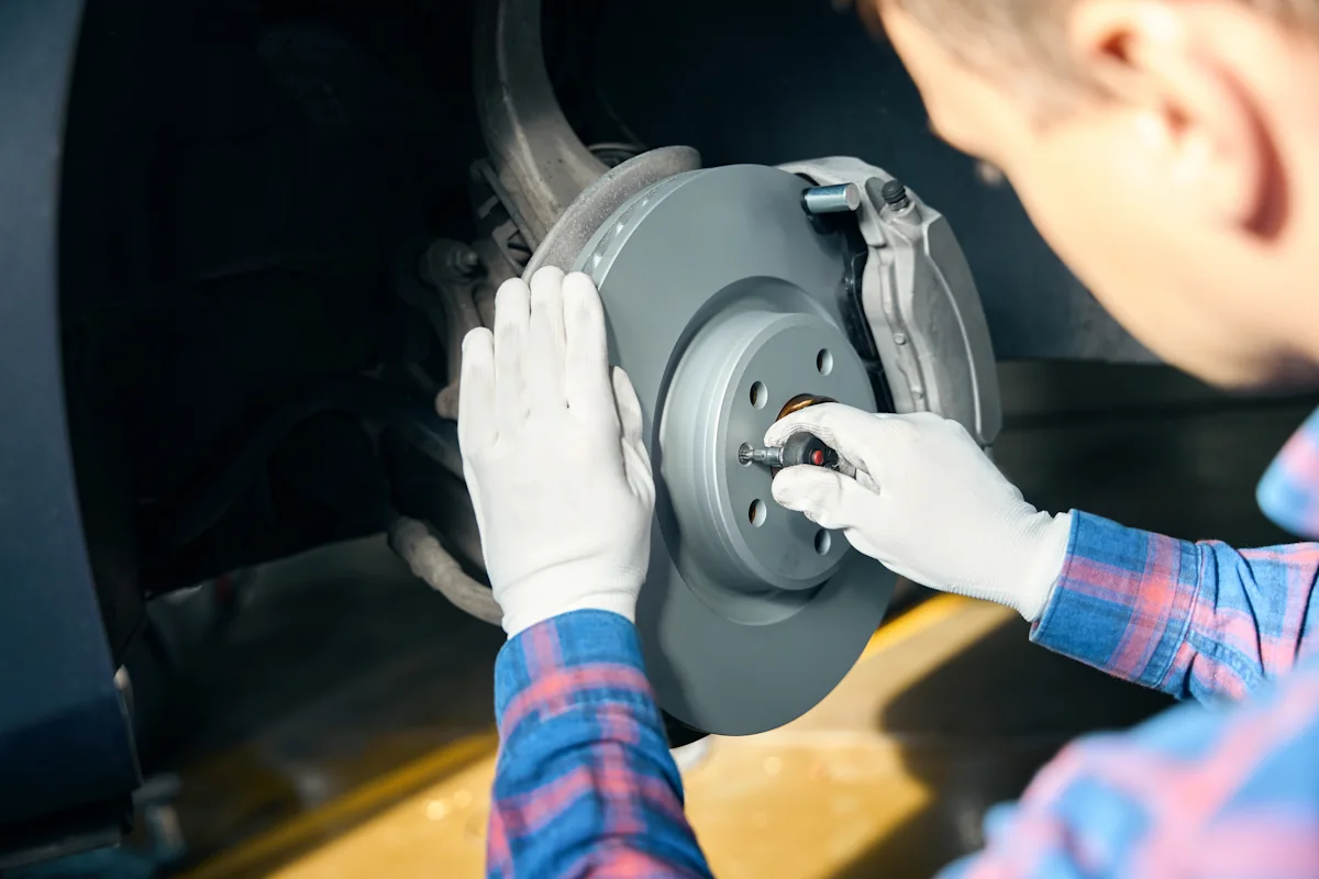 Un homme qui remonte des plaquettes de freins sur une voiture